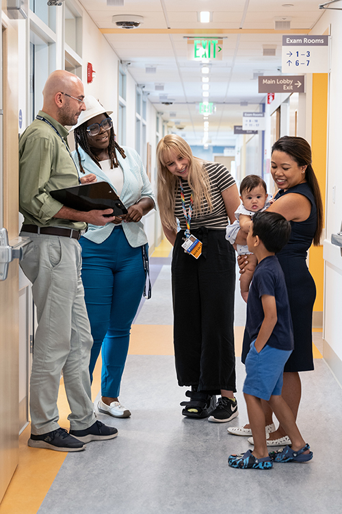 A diverse group of patients, parents, and clinicians in a hallway at RSZ TNC.