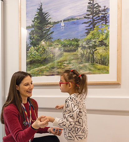 Clinician with child patient with Rosamund Stone Zander painting on the wall behind them